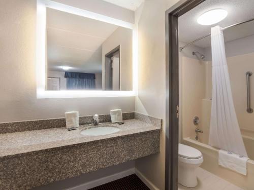 a bathroom with a sink and a toilet and a mirror at Rodeway Inn in Greenwood