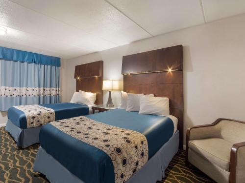 ein Hotelzimmer mit 2 Betten und einem Stuhl in der Unterkunft Rodeway Inn in Greenwood