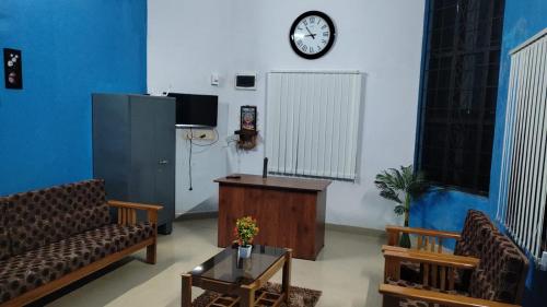 a living room with a couch and a clock on the wall at Malpe Gruham Homestay Udupi in Malpe