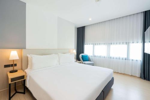 a bedroom with a large white bed and a window at Best Western Nada Don Mueang Airport hotel in Bangkok