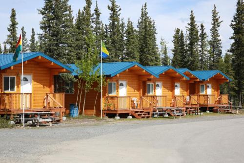 a log cabin with blue roofs and two flags at Tok RV Village and Cabins in Tok