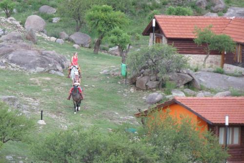 a person riding a horse next to a house at Los Ancares Resort in Mina Clavero