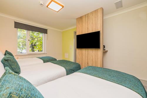 a hotel room with three beds and a flat screen tv at Forty Four Main Street in Swords