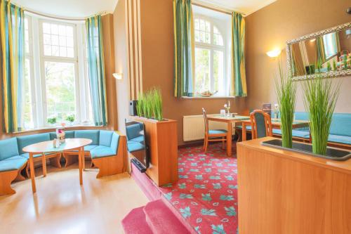a waiting room with chairs and tables and windows at Ferien Hotel Villa Südharz in Sülzhayn