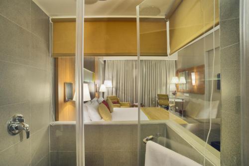 a bathroom with a large mirror of a bedroom at Royal Orchid Central Vadodara in Vadodara