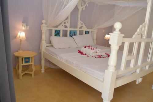 a bedroom with a white bed with a canopy at Pole Pole Beach House in Watamu