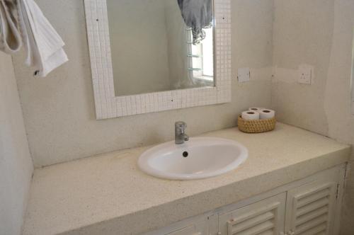 a bathroom counter with a sink and a mirror at Pole Pole Beach House in Watamu