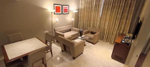 a room with a chair and a table and a desk at Royal Orchid Central Vadodara in Vadodara