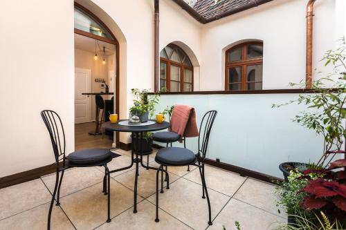eine Terrasse mit einem Tisch und 4 Stühlen in der Unterkunft Apáca 30 Apartman **** Győr in Győr