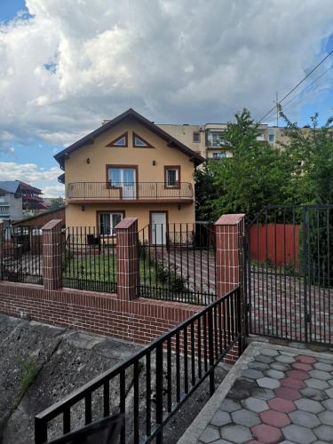 a house behind a black fence with a building at Cozy Villa in Piteşti