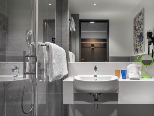 a white bathroom with a sink and a shower at the niu Fury in Aschheim