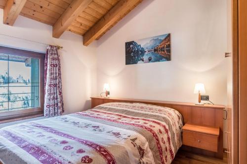 Schlafzimmer mit einem Bett und einem Fenster in der Unterkunft Mansarda Pinè in Bedollo