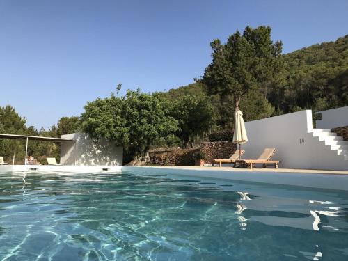 a pool with an umbrella and a table and a chair at White House Ibiza Modernist Design Can Perez Sea views Es Figueral in Santa Eularia des Riu