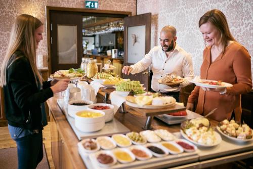 a group of people standing around a buffet of food at First Hotel Bengtsfors in Bengtsfors