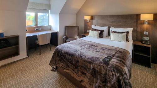 a hotel room with a large bed and a desk at Coppid Beech in Bracknell