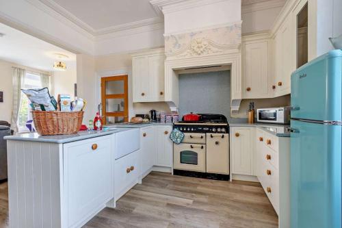 a kitchen with white cabinets and a blue refrigerator at Dizzy Heights Swanage Sleeps 10 with Amazing Views in Swanage