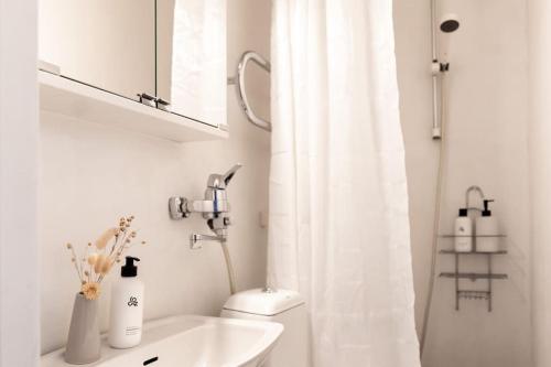 a white bathroom with a toilet and a sink at Luminous studio in Kallio / Amazing location in Helsinki