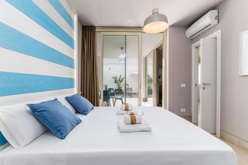 1 dormitorio con 1 cama blanca grande con almohadas azules en Mare Villas Pescoluse- Design Apartment, en Marina di Pescoluse