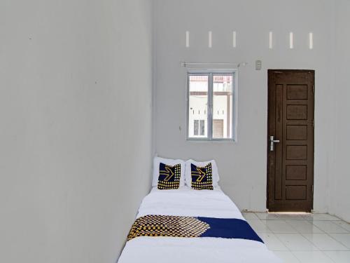 1 cama en una habitación blanca con 2 almohadas en SPOT ON 91828 Homestay Dinda Syariah, en Parit