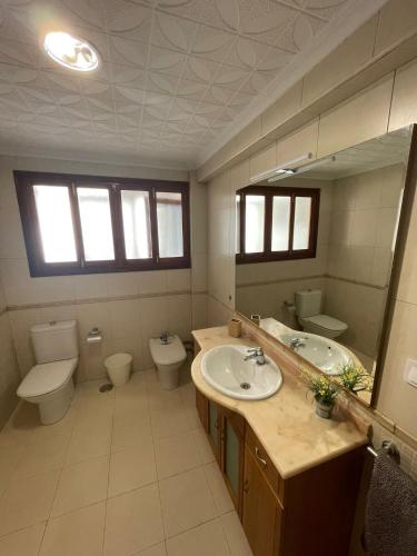 ein Badezimmer mit zwei Waschbecken, einem WC und einem Spiegel in der Unterkunft Gran apartamento con la playa a 2 kilómetros para familias in San Juan de Alicante