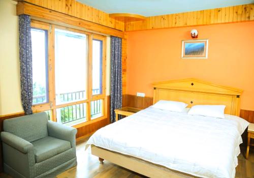 a bedroom with a bed and a chair at Hari Om Paradise in Kūfrī
