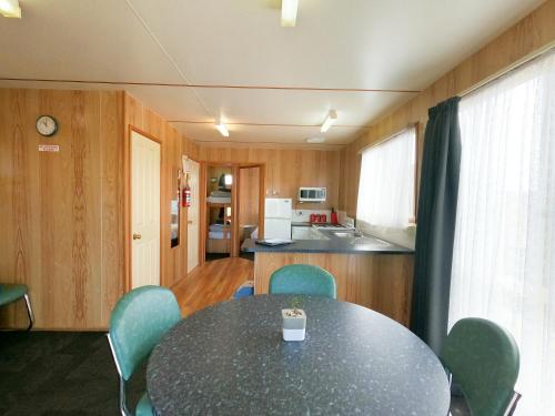 a dining room with a table and chairs and a kitchen at BIG4 Ulverstone Holiday Park in Ulverstone