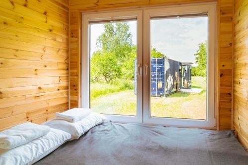 Bett in einem Zimmer mit einem großen Fenster in der Unterkunft Arche Siedlisko Rogacze 72 in Milejczyce