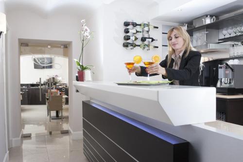 a woman standing at a counter with two drinks at Demetra Hotel in Rome