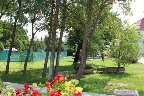 a park with trees and flowers in the grass at Rábensteiner Panzió in Fertőd