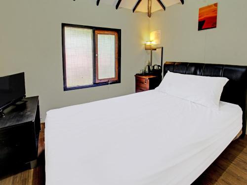 1 dormitorio con 1 cama blanca y TV en OYO 91830 Hotel Gemilang 2, en Lombok
