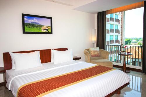 a bedroom with a large bed and a balcony at Grand Surya Hotel Kediri in Kediri