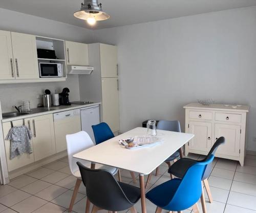 een keuken met een witte tafel en blauwe stoelen bij Appartement avec Sauna et Piscine au bord de mer in Plougonvelin