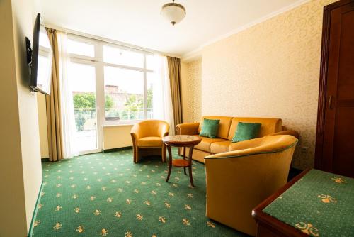 a hotel room with a couch and chairs and a table at Elizabeth Hotel in Gyula