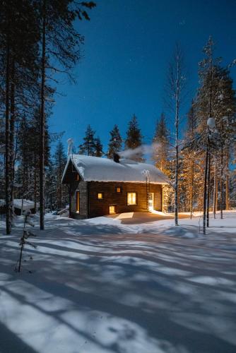 a log cabin in the snow at night at Black Work Levi Aihki in Kittilä