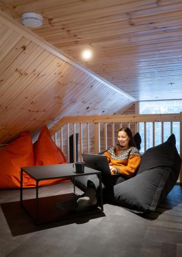 a woman sitting on a couch with a laptop at Black Work Levi Aihki in Kittilä
