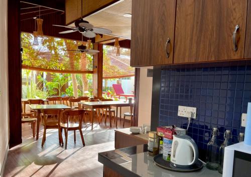 a kitchen with wooden cabinets and a dining room with tables at Shark lounge in Fuvahmulah