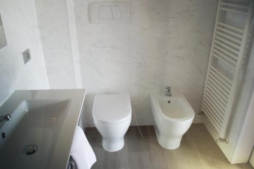 a white bathroom with a toilet and a bidet at Residence La Quiete in Alba