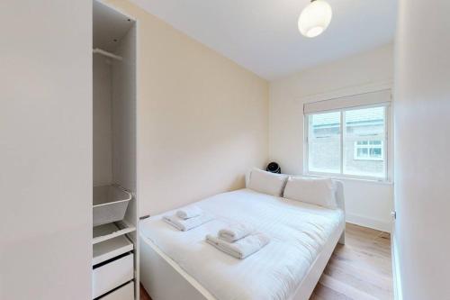 Un pequeño dormitorio con una cama blanca y una ventana en Lovely 2-bedroom flat with parking near Highgate en Londres