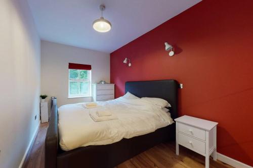 a bedroom with a red wall with a bed at Lovely 2-bedroom flat with parking near Highgate in London