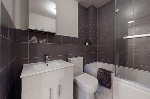 een badkamer met een toilet, een wastafel en een bad bij Lovely 2-bedroom flat with parking near Highgate in Londen