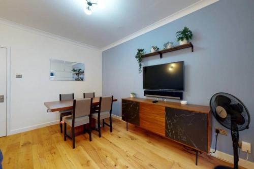 een woonkamer met een eettafel en een flatscreen-tv bij Lovely 2-bedroom flat with parking near Highgate in Londen