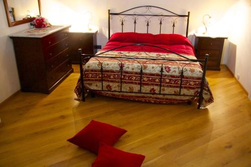 a bedroom with a bed with red pillows on a wooden floor at Papparina House in Marsala
