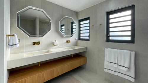 a bathroom with a sink and two mirrors at Luxury Villa Beach and Putt avec accès plage in Saint-François