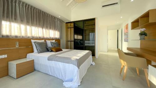 a bedroom with a large bed and a desk and a desk at Luxury Villa Beach and Putt avec accès plage in Saint-François