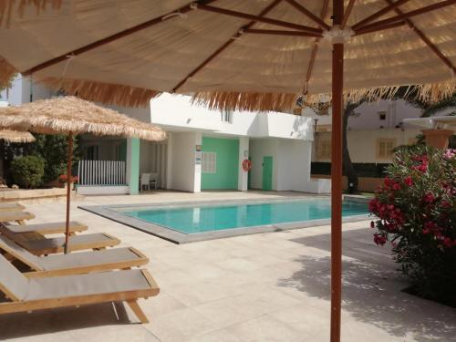 a pool with umbrellas and lounge chairs and a swimming pool at Apartaments Andreas in Colonia Sant Jordi