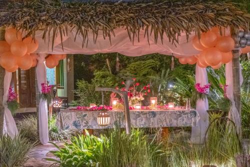 a table under a gazebo with flowers and a table with a table at Kanlaya's Eyrie, Luxury Homestay in Pang Mapha