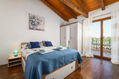 a bedroom with a bed with a blue blanket on it at Villa Marijanin Vrt in Tinjan