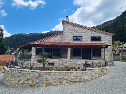 a house on a stone wall in front of a mountain at Omalia Village in Áno Khóra