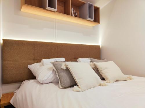 a bed with white pillows in a room at Masuria Resort Village, całoroczne domki z widokiem na jezioro, sauna i jacuzzi in Żywki