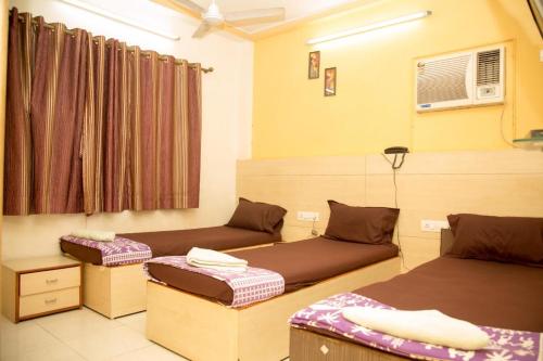 a room with two beds and a window at Srujan Sarai Service Apartment in Mumbai